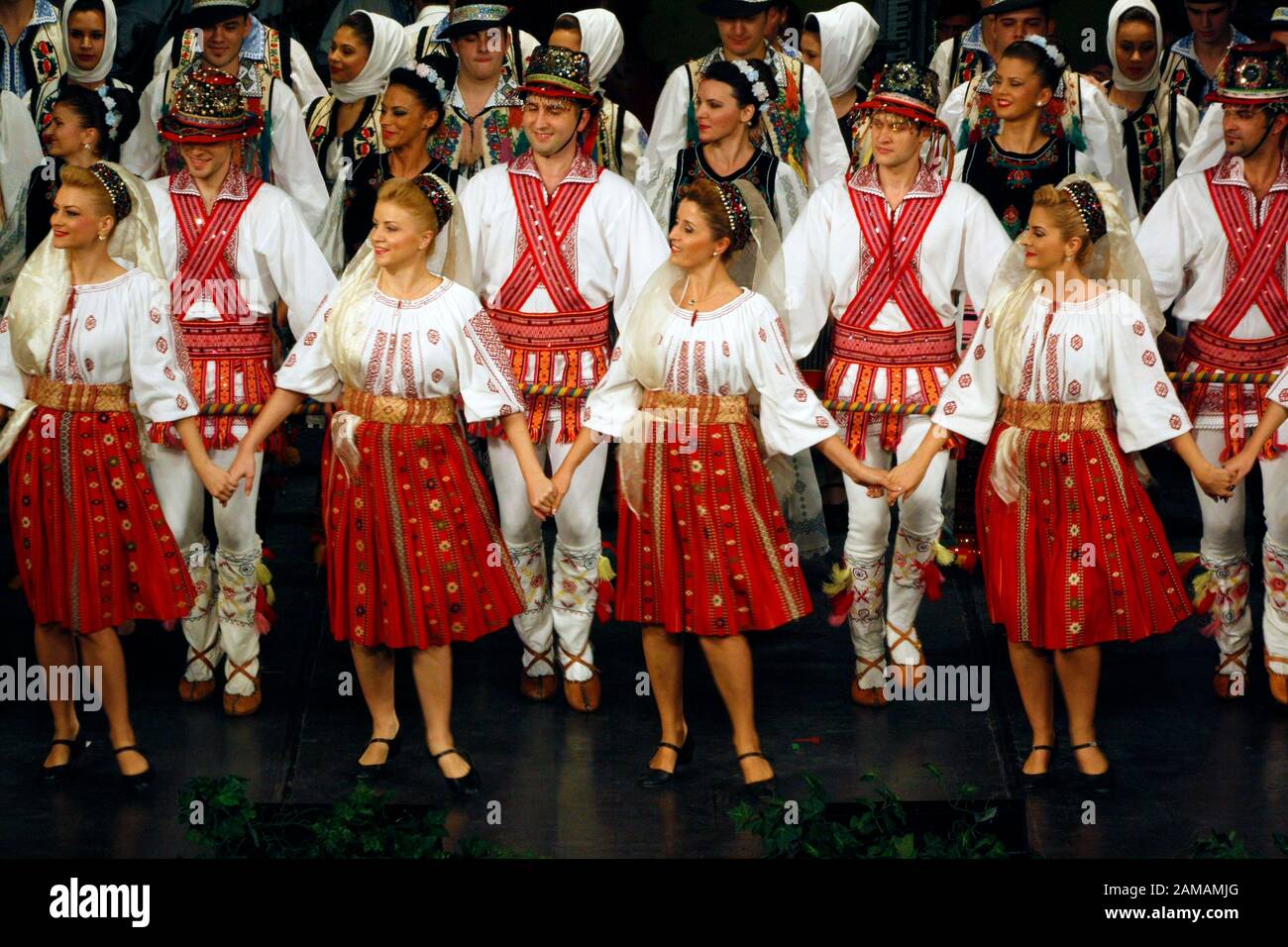 I ballerini professionisti del Banatul Folklore Ensemble tengono le mani in una danza tradizionale rumena indossando costumi tradizionali belli. Foto Stock