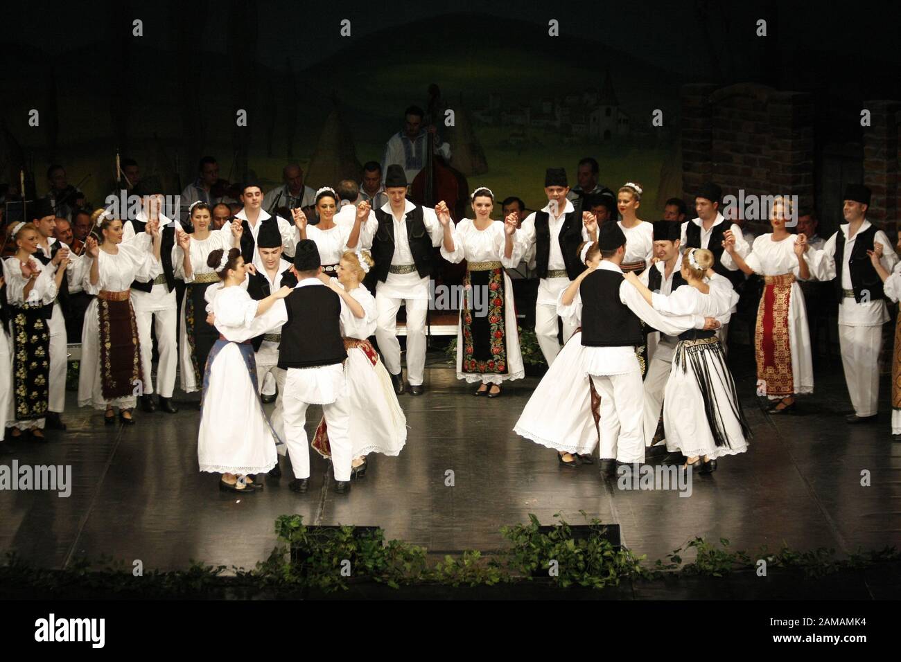 I ballerini professionisti del Banatul Folklore Ensemble tengono le mani in una danza tradizionale rumena indossando costumi tradizionali belli. Foto Stock