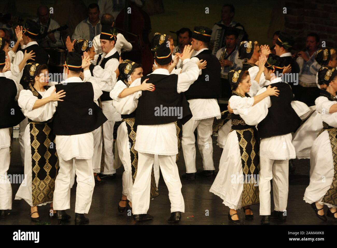 I ballerini professionisti del Banatul Folklore Ensemble tengono le mani in una danza tradizionale rumena indossando costumi tradizionali belli. Foto Stock
