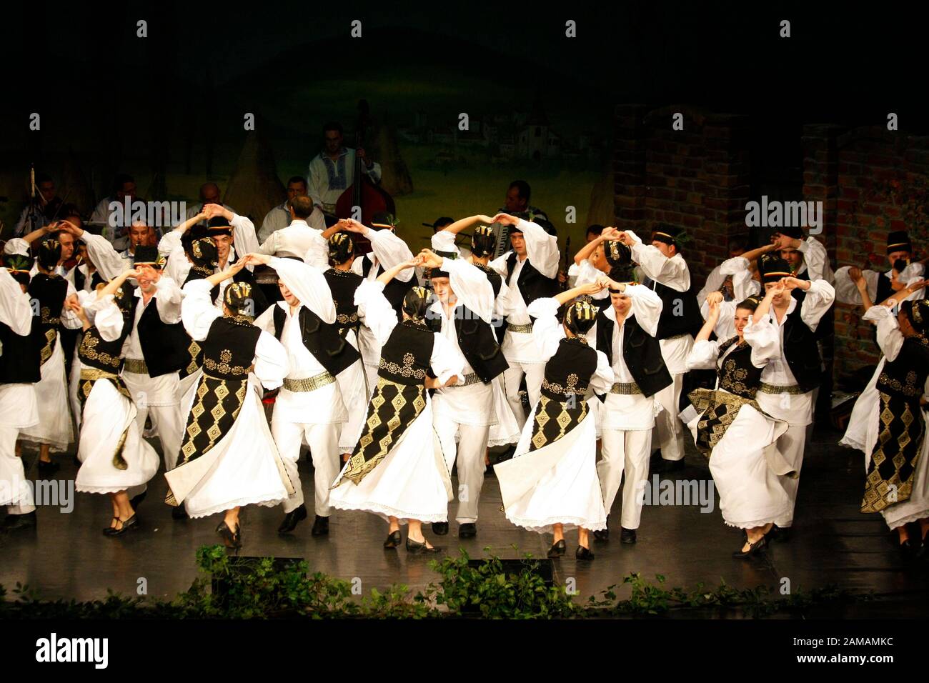 I ballerini professionisti del Banatul Folklore Ensemble tengono le mani in una danza tradizionale rumena indossando costumi tradizionali belli. Foto Stock