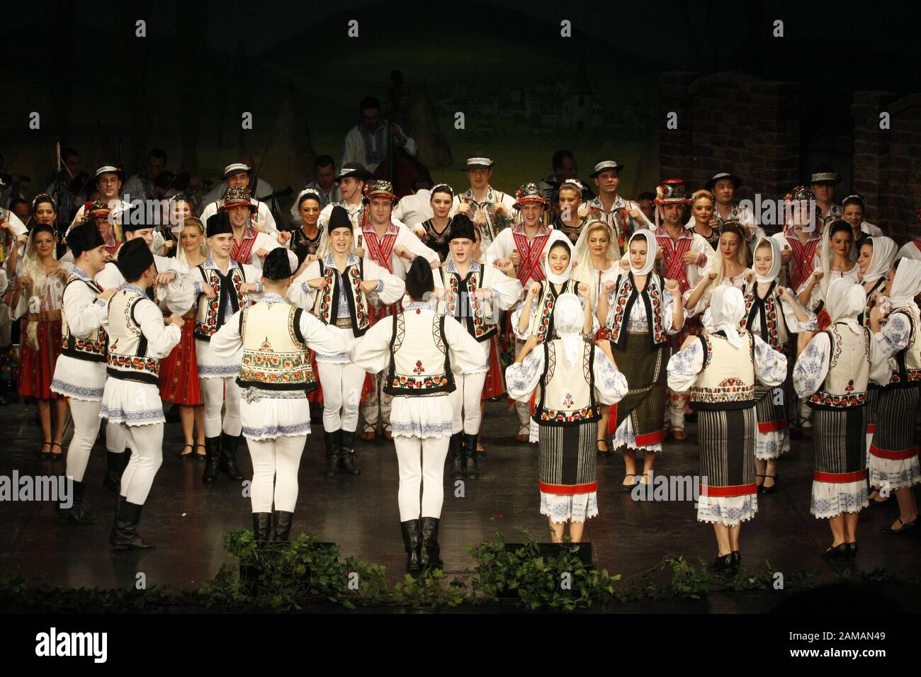 I ballerini professionisti del Banatul Folklore Ensemble tengono le mani in una danza tradizionale rumena indossando costumi tradizionali belli. Foto Stock