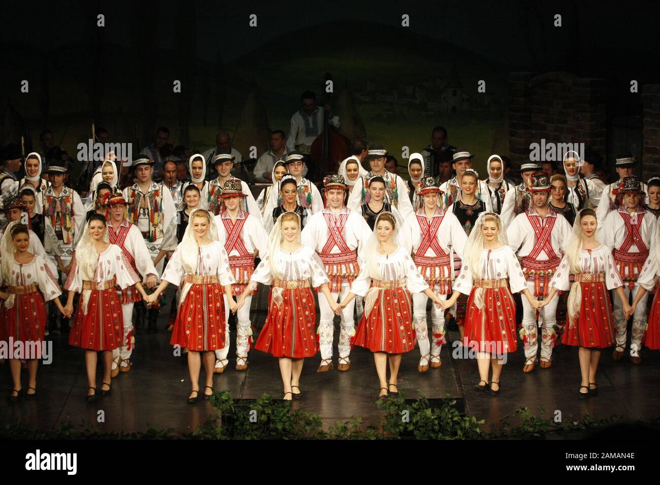 I ballerini professionisti del Banatul Folklore Ensemble tengono le mani in una danza tradizionale rumena indossando costumi tradizionali belli. Foto Stock