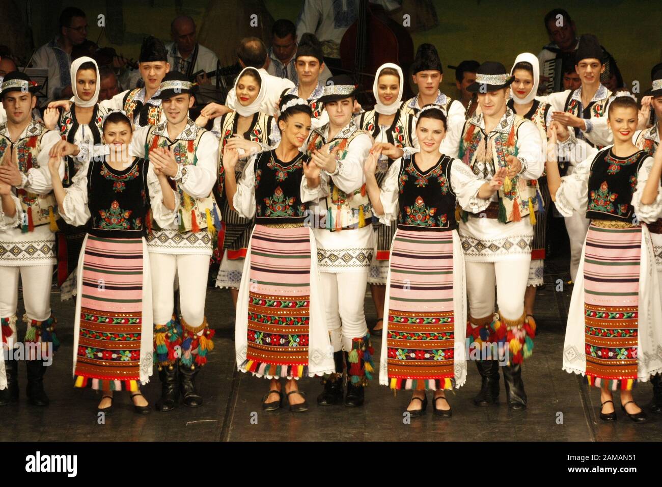 I ballerini professionisti del Banatul Folklore Ensemble tengono le mani in una danza tradizionale rumena indossando costumi tradizionali belli. Foto Stock