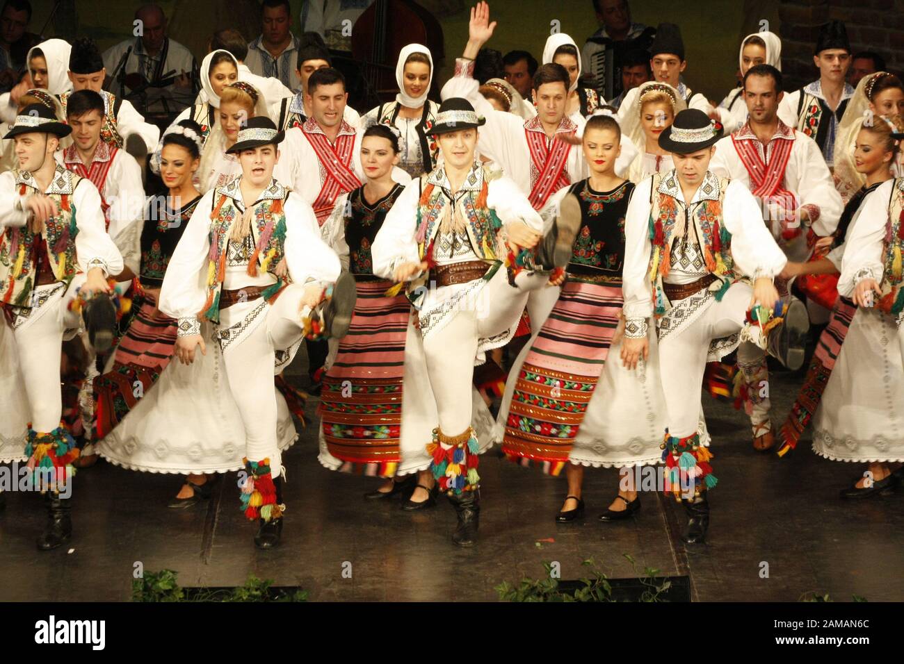 I ballerini professionisti del Banatul Folklore Ensemble tengono le mani in una danza tradizionale rumena indossando costumi tradizionali belli. Foto Stock