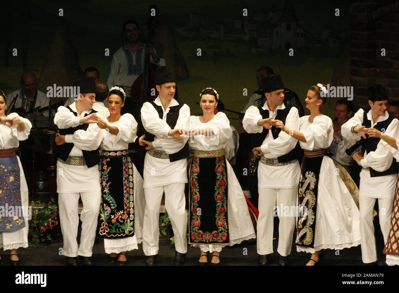 I ballerini professionisti del Banatul Folklore Ensemble tengono le mani in una danza tradizionale rumena indossando costumi tradizionali belli. Foto Stock