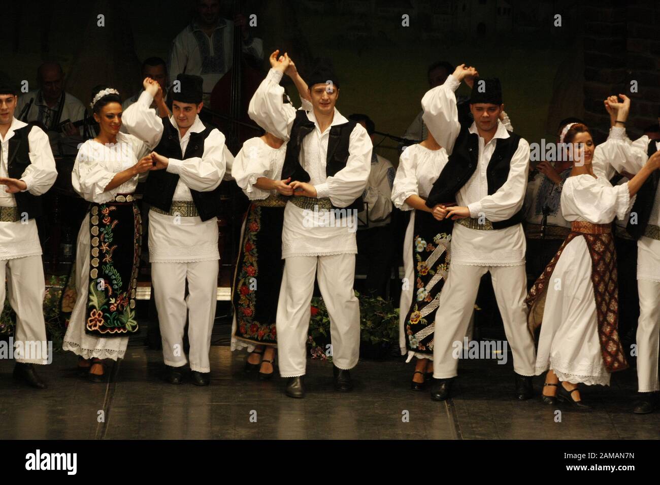 I ballerini professionisti del Banatul Folklore Ensemble tengono le mani in una danza tradizionale rumena indossando costumi tradizionali belli. Foto Stock