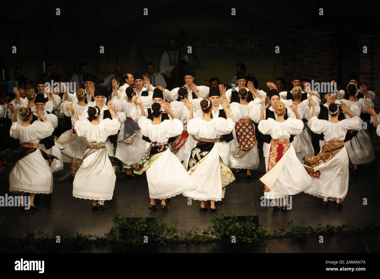 I ballerini professionisti del Banatul Folklore Ensemble tengono le mani in una danza tradizionale rumena indossando costumi tradizionali belli. Foto Stock