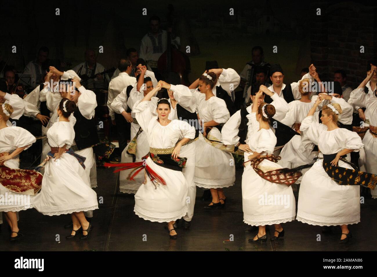I ballerini professionisti del Banatul Folklore Ensemble tengono le mani in una danza tradizionale rumena indossando costumi tradizionali belli. Foto Stock