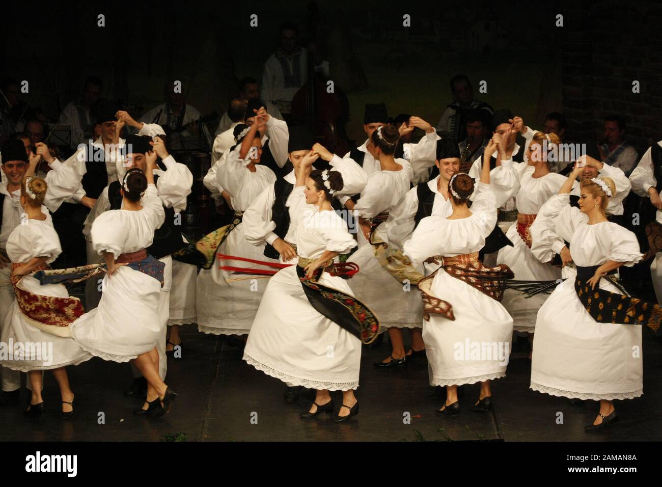 I ballerini professionisti del Banatul Folklore Ensemble tengono le mani in una danza tradizionale rumena indossando costumi tradizionali belli. Foto Stock
