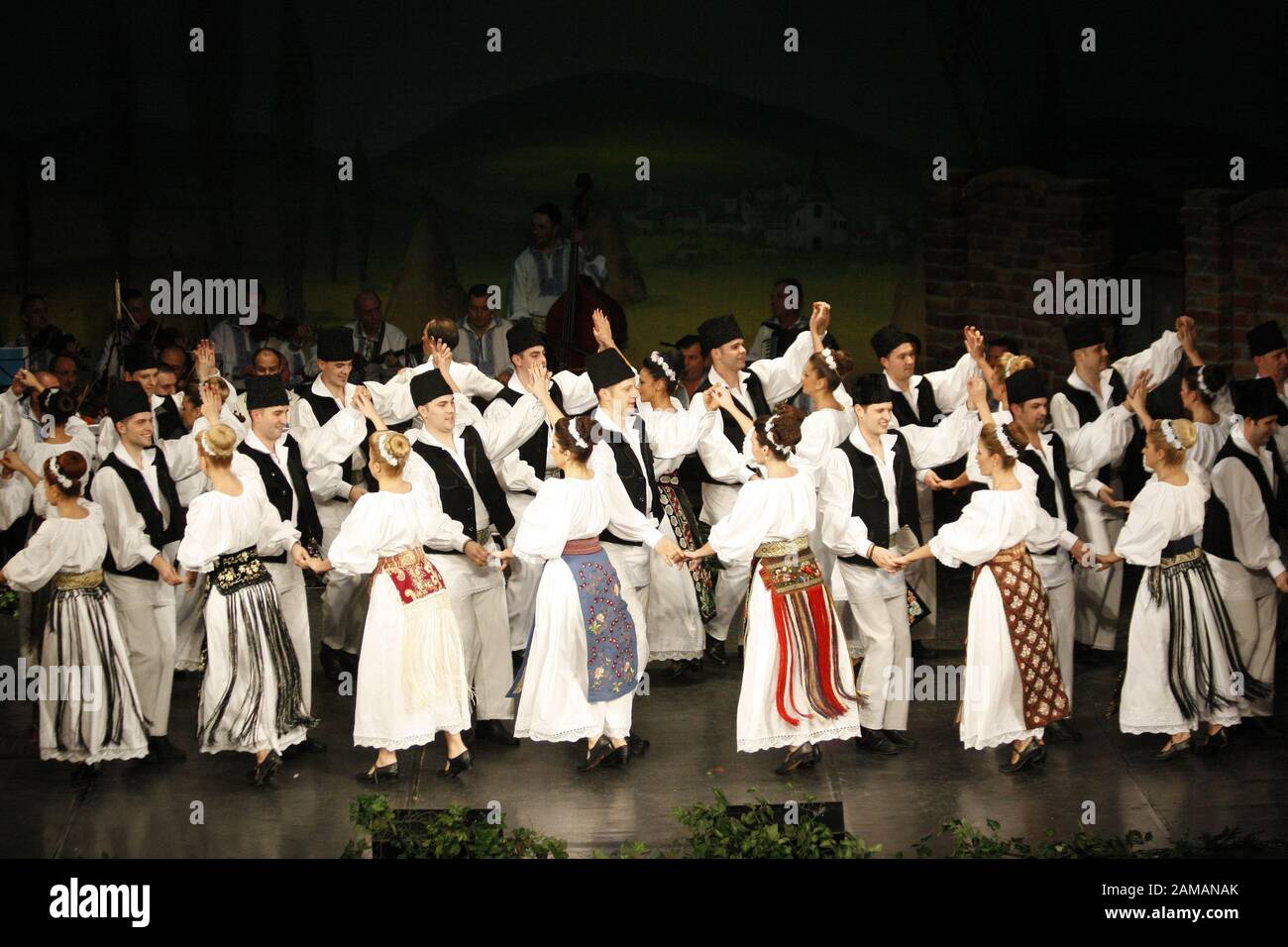 I ballerini professionisti del Banatul Folklore Ensemble tengono le mani in una danza tradizionale rumena indossando costumi tradizionali belli. Foto Stock