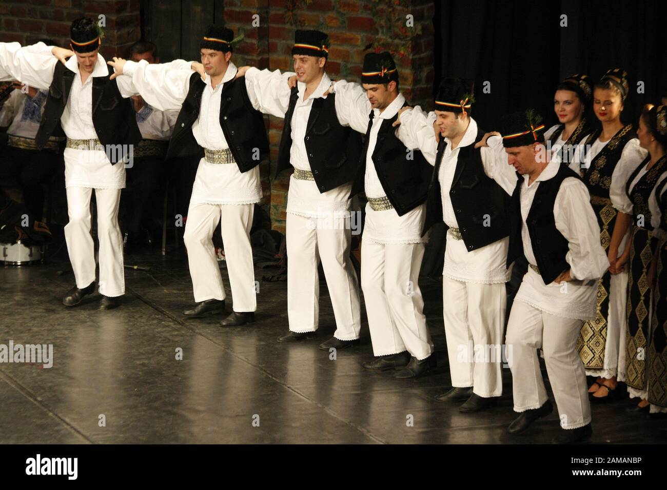 I ballerini professionisti del Banatul Folklore Ensemble tengono le mani in una danza tradizionale rumena indossando costumi tradizionali belli. Foto Stock
