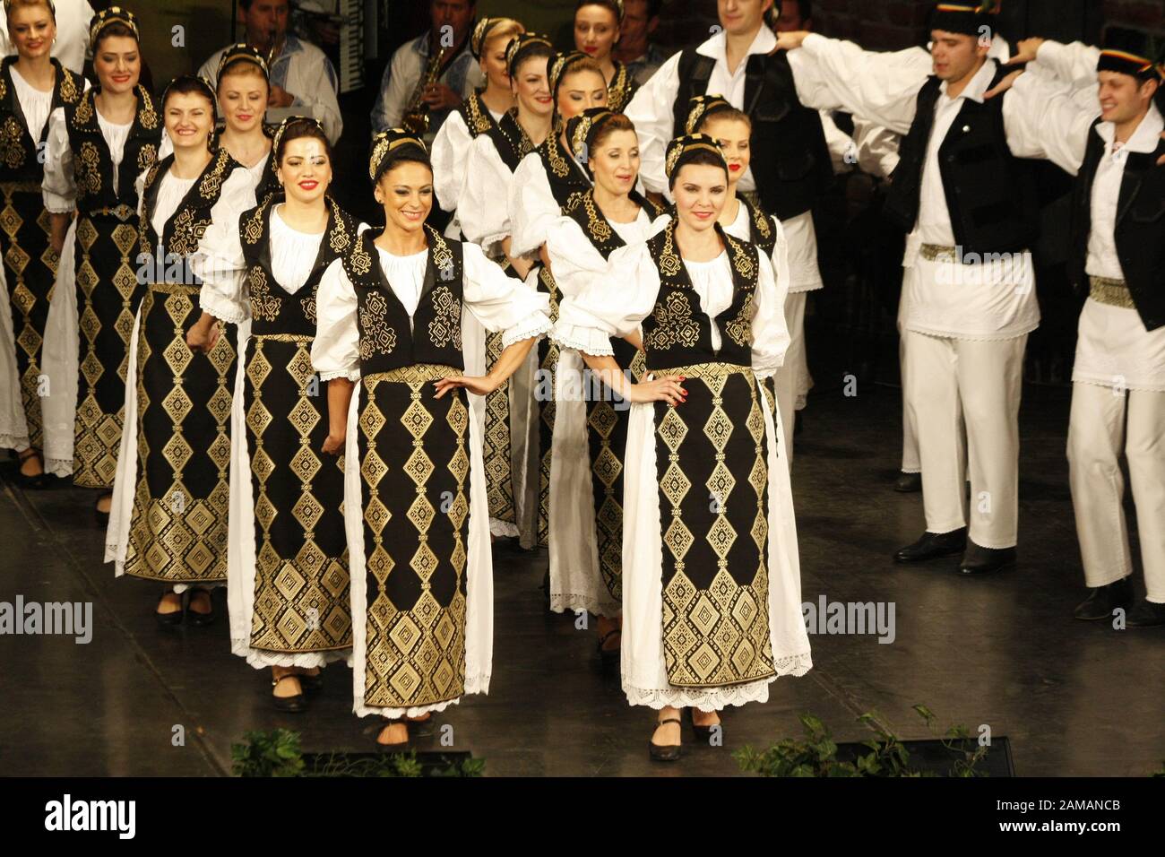 I ballerini professionisti del Banatul Folklore Ensemble tengono le mani in una danza tradizionale rumena indossando costumi tradizionali belli. Foto Stock