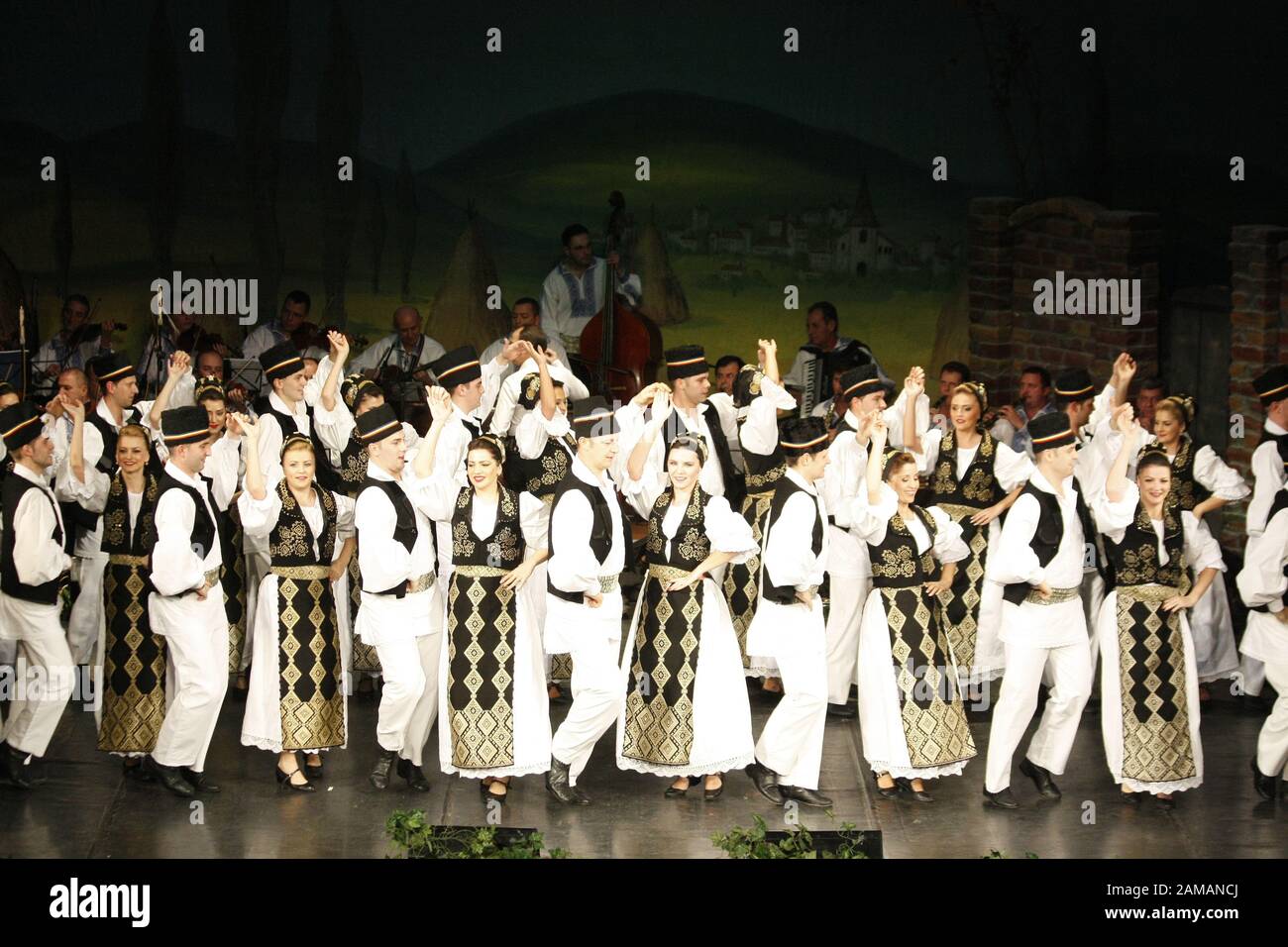 I ballerini professionisti del Banatul Folklore Ensemble tengono le mani in una danza tradizionale rumena indossando costumi tradizionali belli. Foto Stock