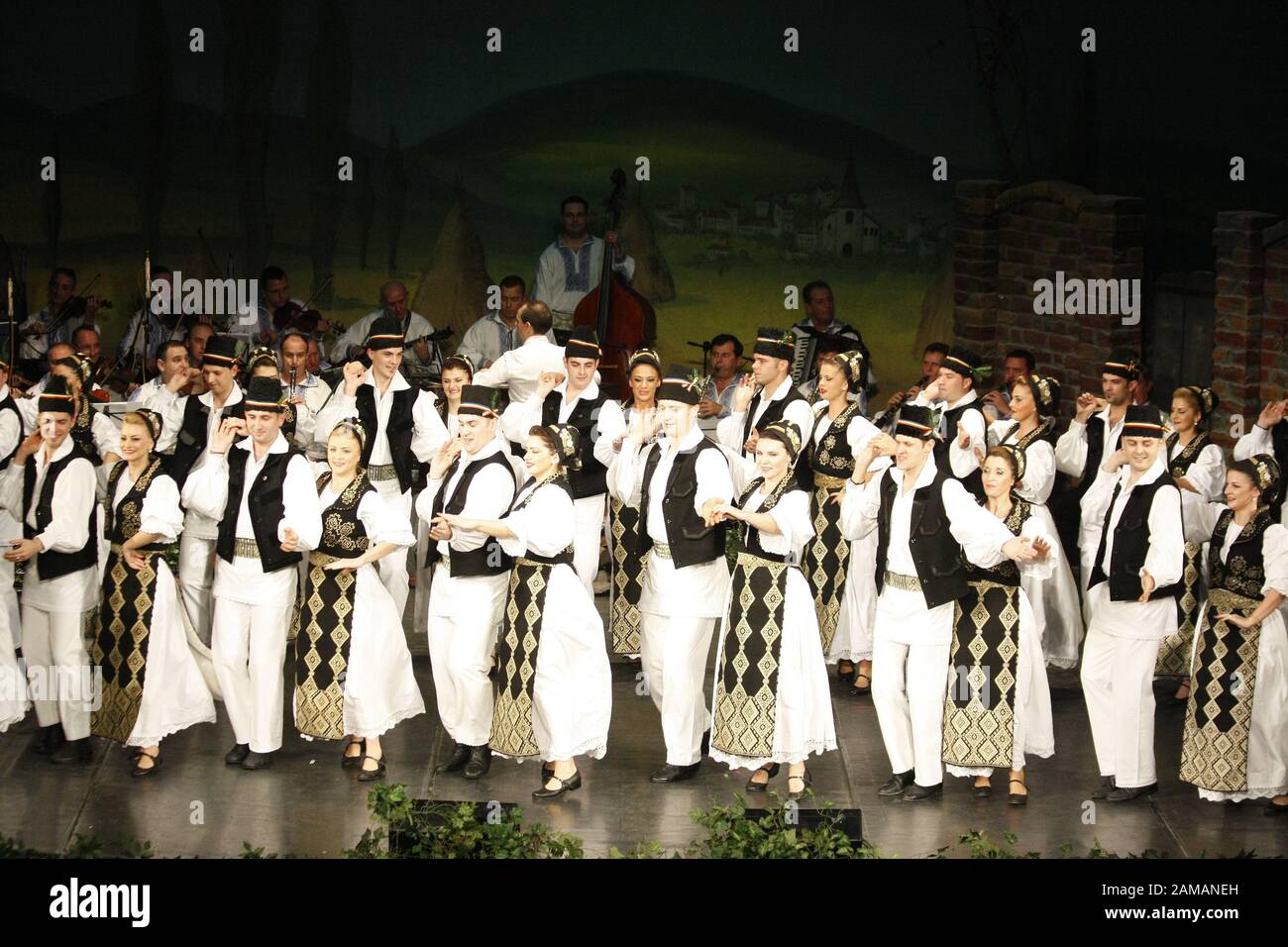 I ballerini professionisti del Banatul Folklore Ensemble tengono le mani in una danza tradizionale rumena indossando costumi tradizionali belli. Foto Stock