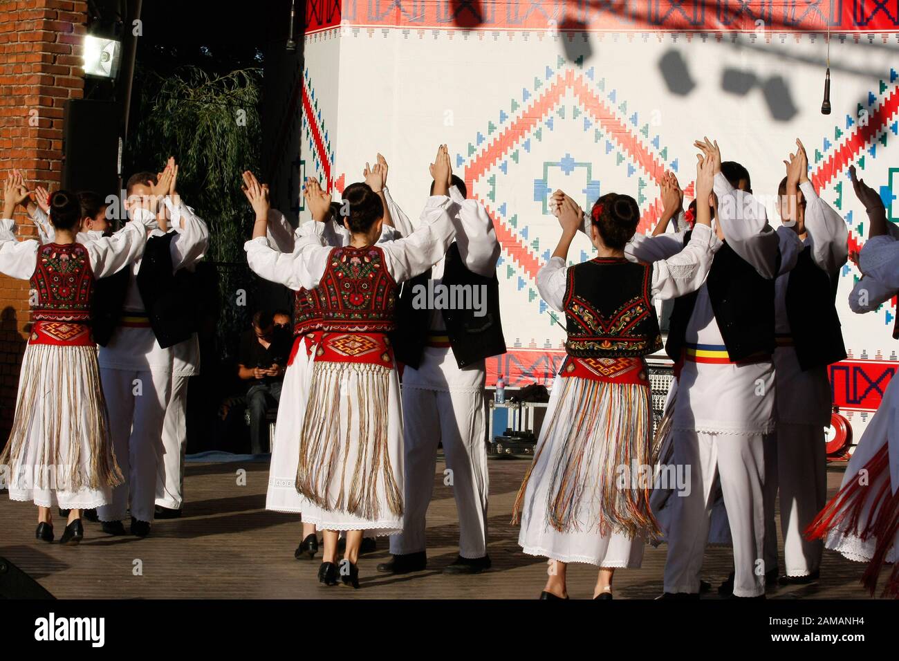 I ballerini professionisti del Banatul Folklore Ensemble tengono le mani in una danza tradizionale rumena indossando costumi tradizionali belli. Foto Stock
