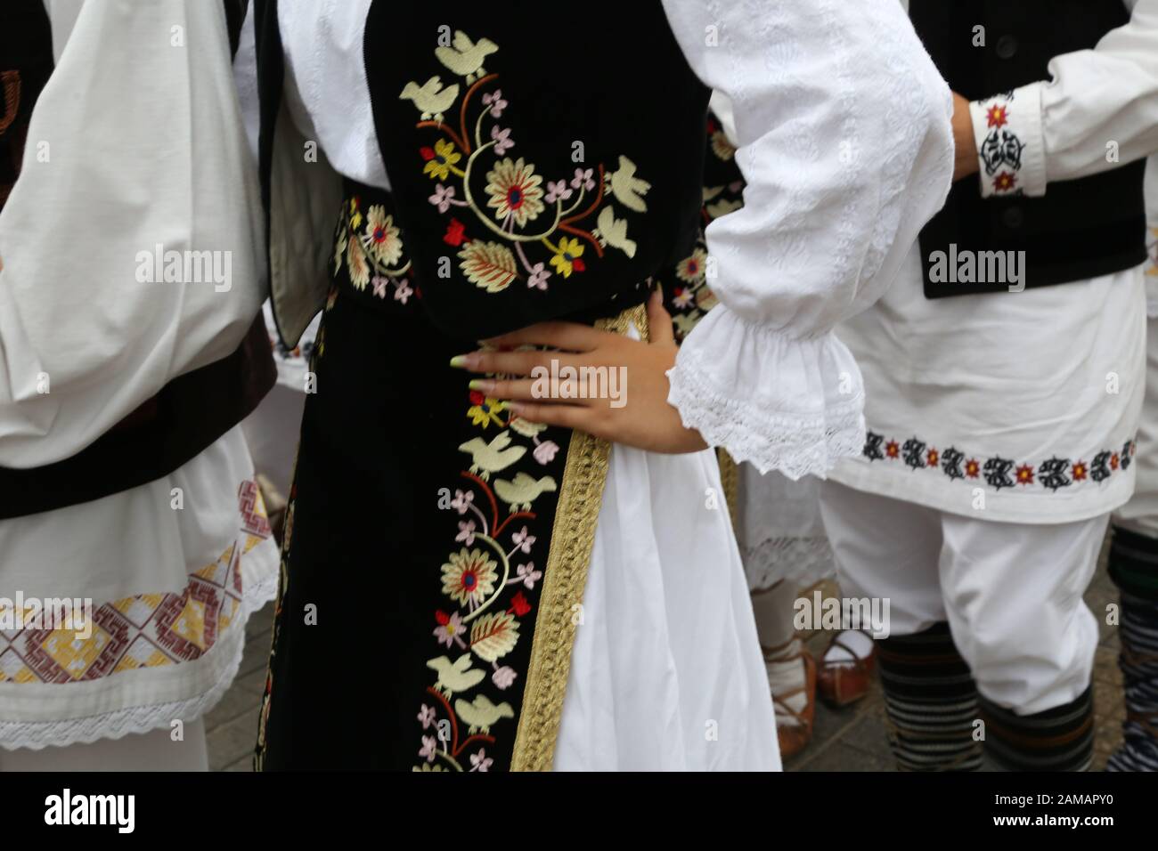 I ballerini professionisti del Timisul Folklore Ensemble tengono le mani in una danza tradizionale rumena indossando costumi tradizionali belli. Foto Stock