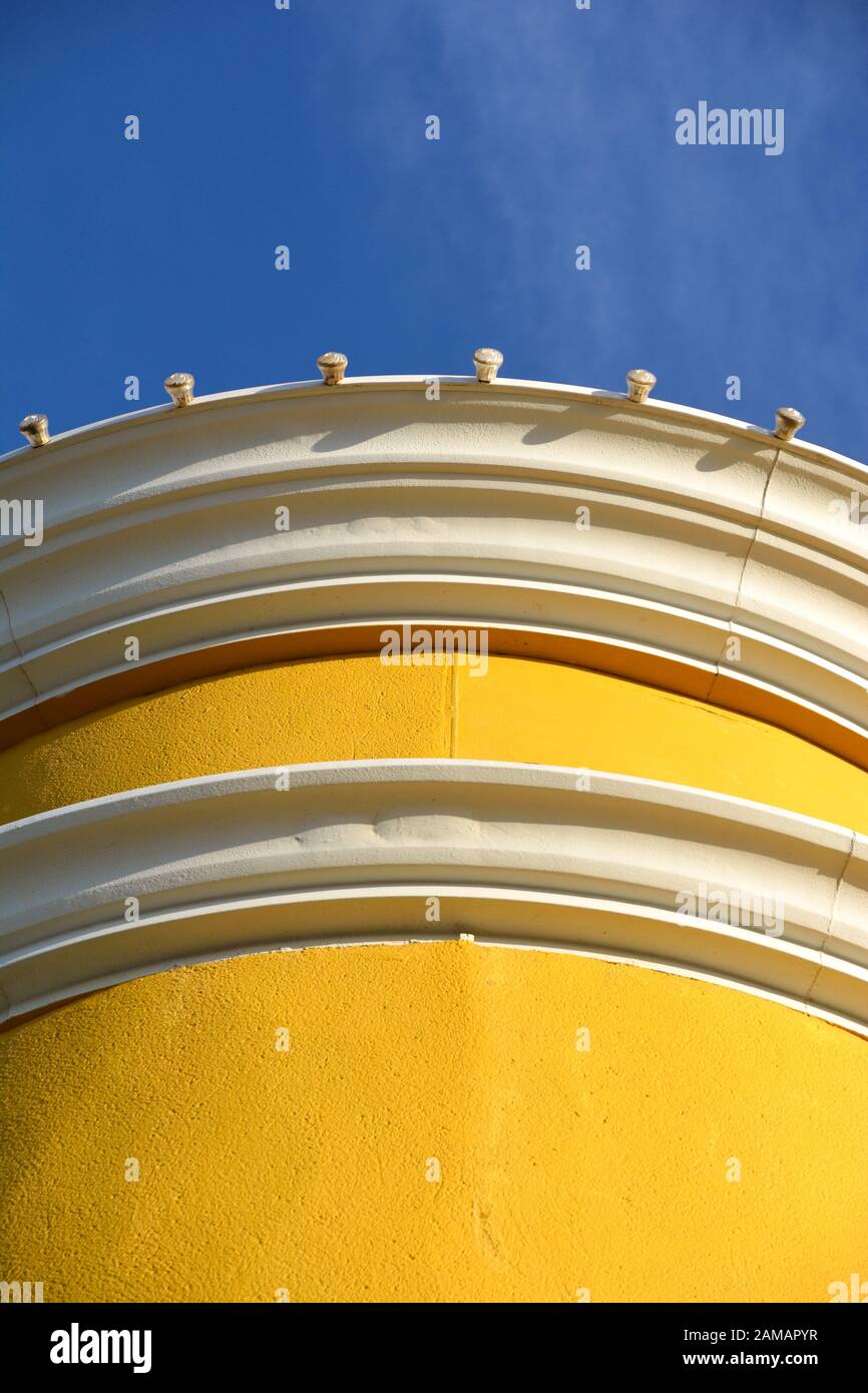 Un allegro edificio giallo con una forma arrotondata serie anteriore contro un luminoso cielo blu in una giornata di sole Foto Stock