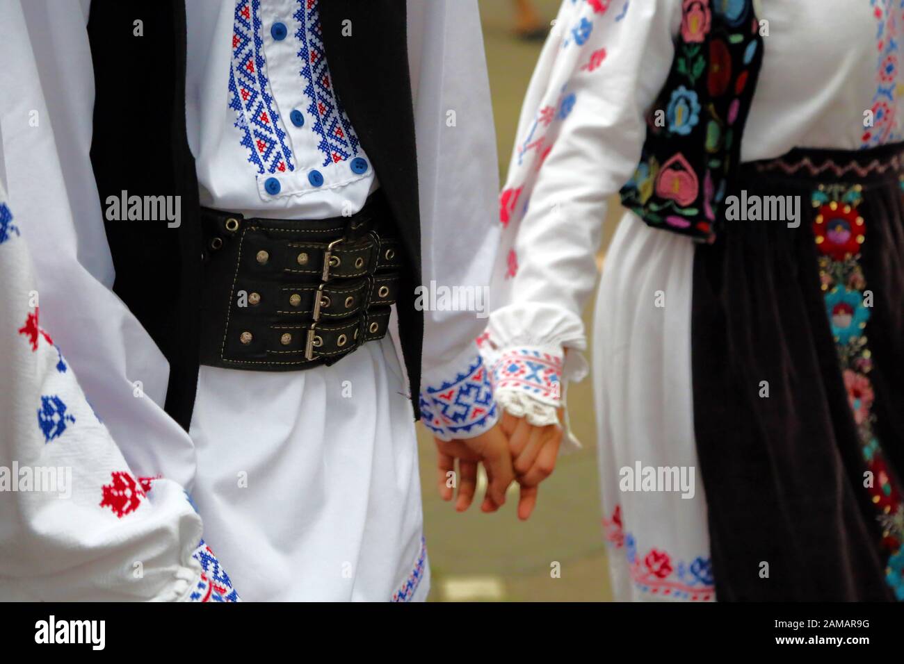 I ballerini professionisti del Timisul Folklore Ensemble tengono le mani in una danza tradizionale rumena indossando costumi tradizionali belli. Foto Stock