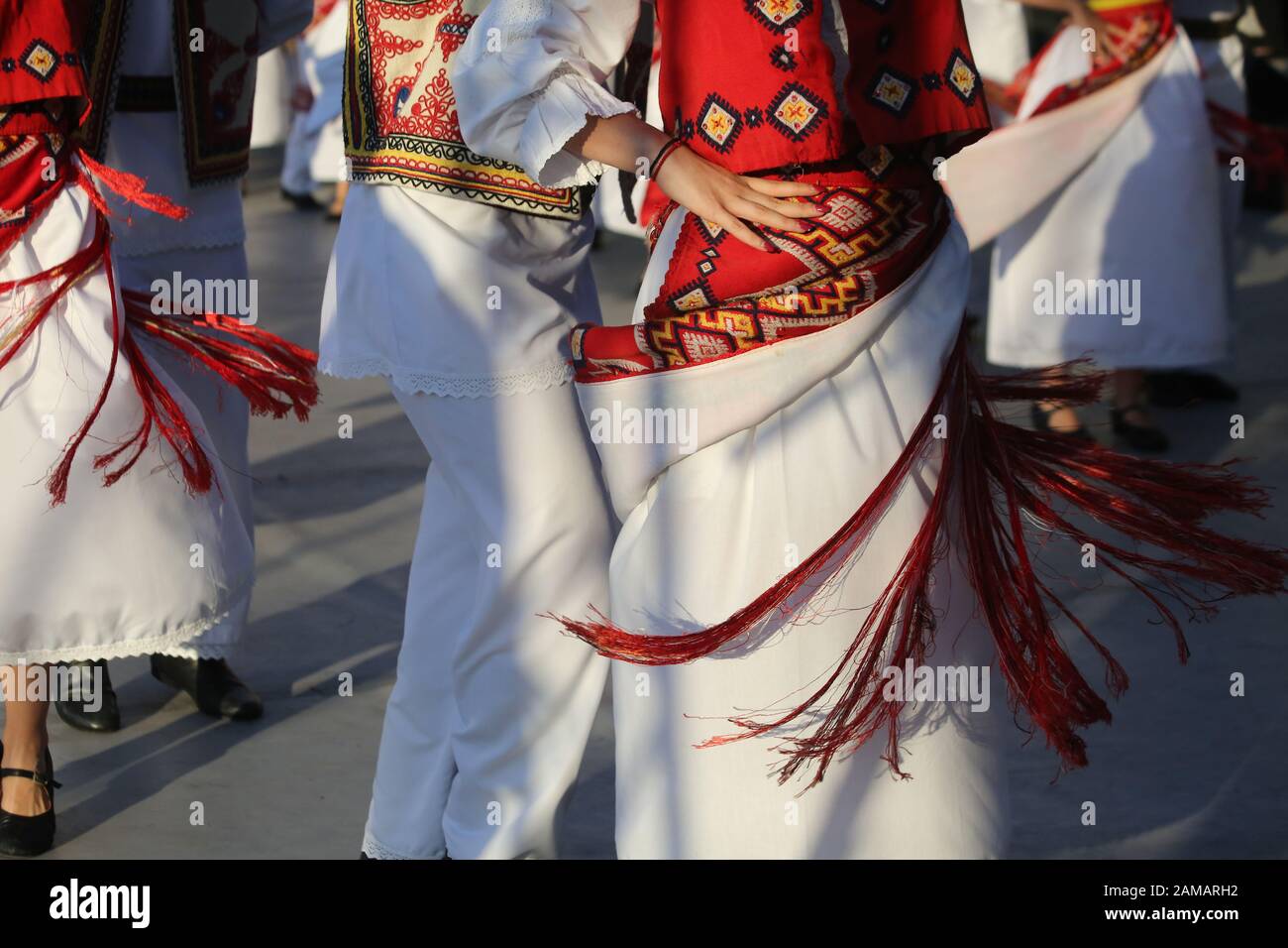 I ballerini professionisti del Timisul Folklore Ensemble tengono le mani in una danza tradizionale rumena indossando costumi tradizionali belli. Foto Stock