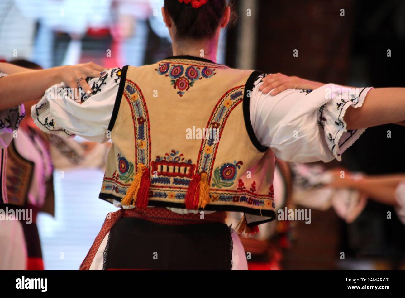 I ballerini professionisti del Timisul Folklore Ensemble tengono le mani in una danza tradizionale rumena indossando costumi tradizionali belli. Foto Stock
