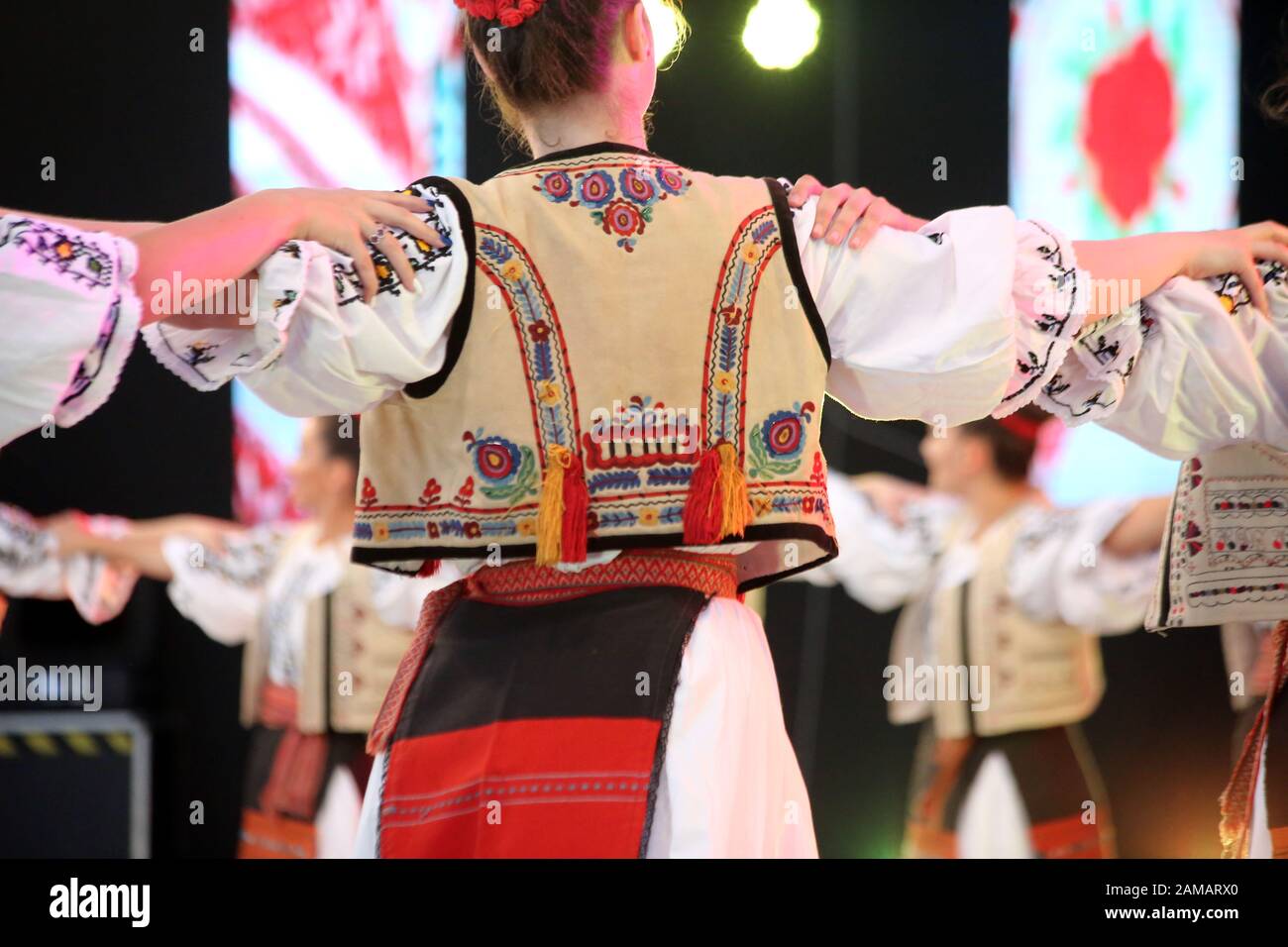 I ballerini professionisti del Timisul Folklore Ensemble tengono le mani in una danza tradizionale rumena indossando costumi tradizionali belli. Foto Stock