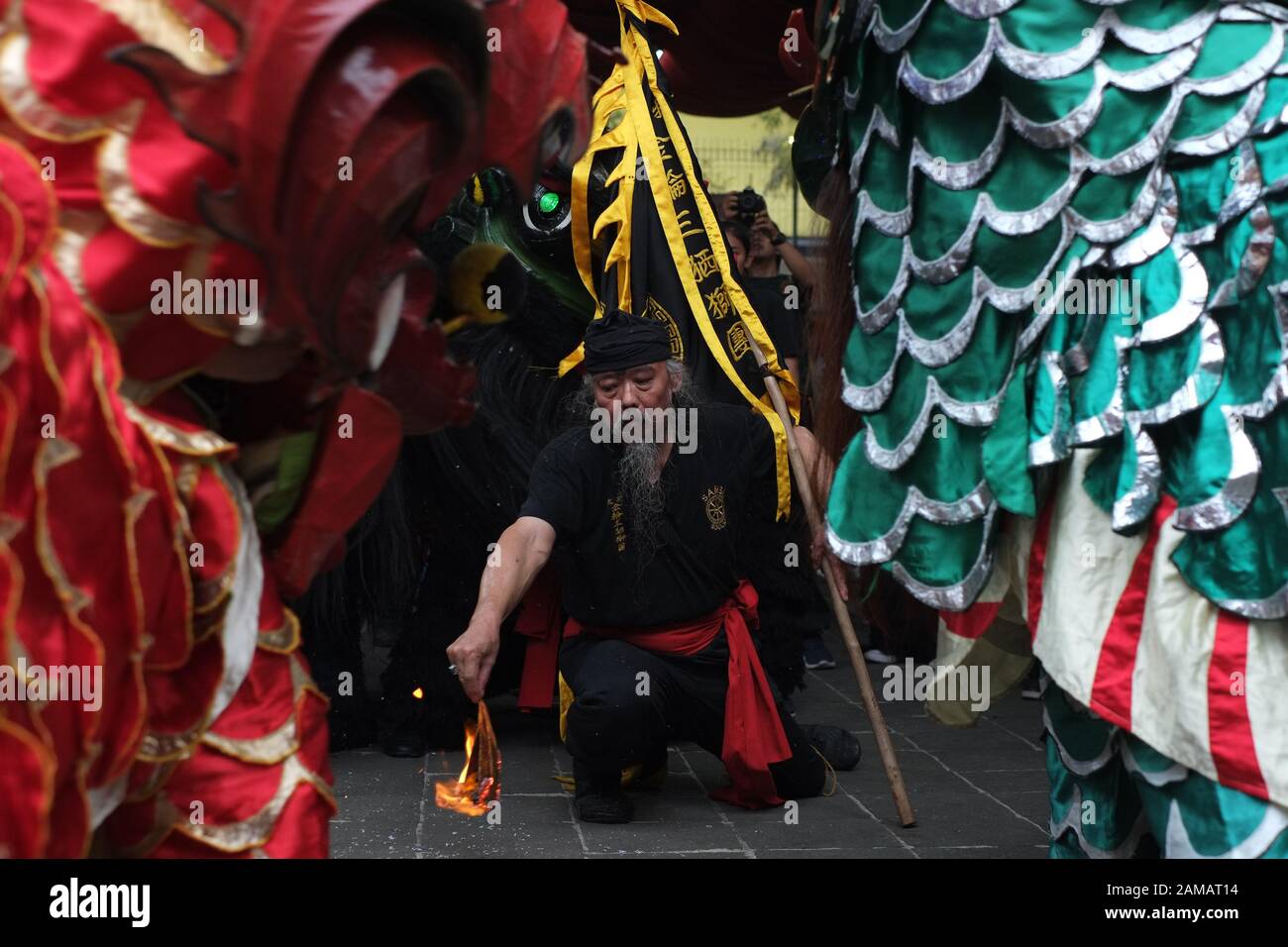 Un uomo anziano con bandiera accende un fuoco come segnale a lion dancer per iniziare le loro prestazioni in celebrazione del Capodanno cinese festival. Foto Stock