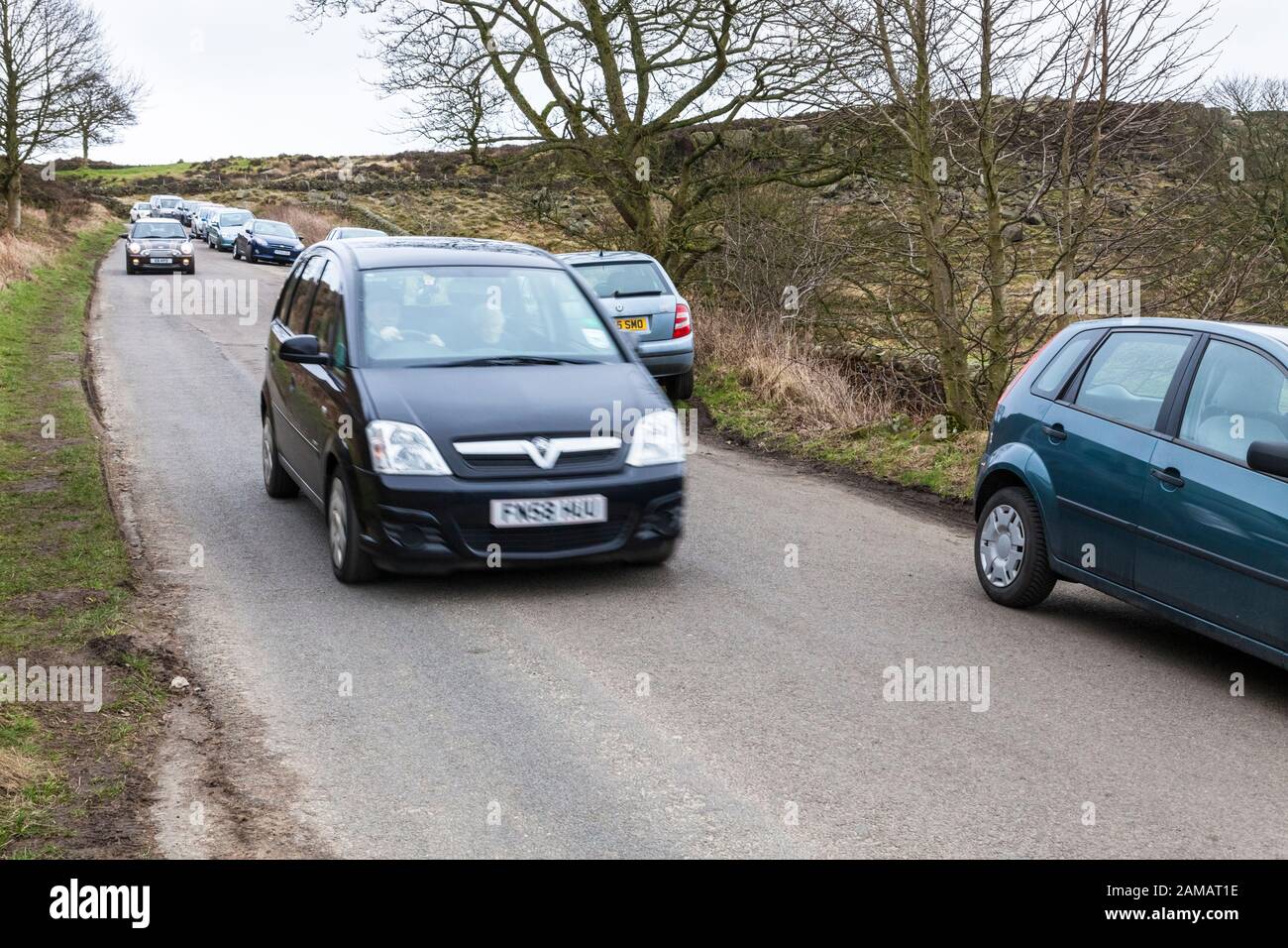 Il traffico su una stretta strada di campagna con molte automobili parcheggiate vicino Curbar, Derbyshire, England, Regno Unito Foto Stock