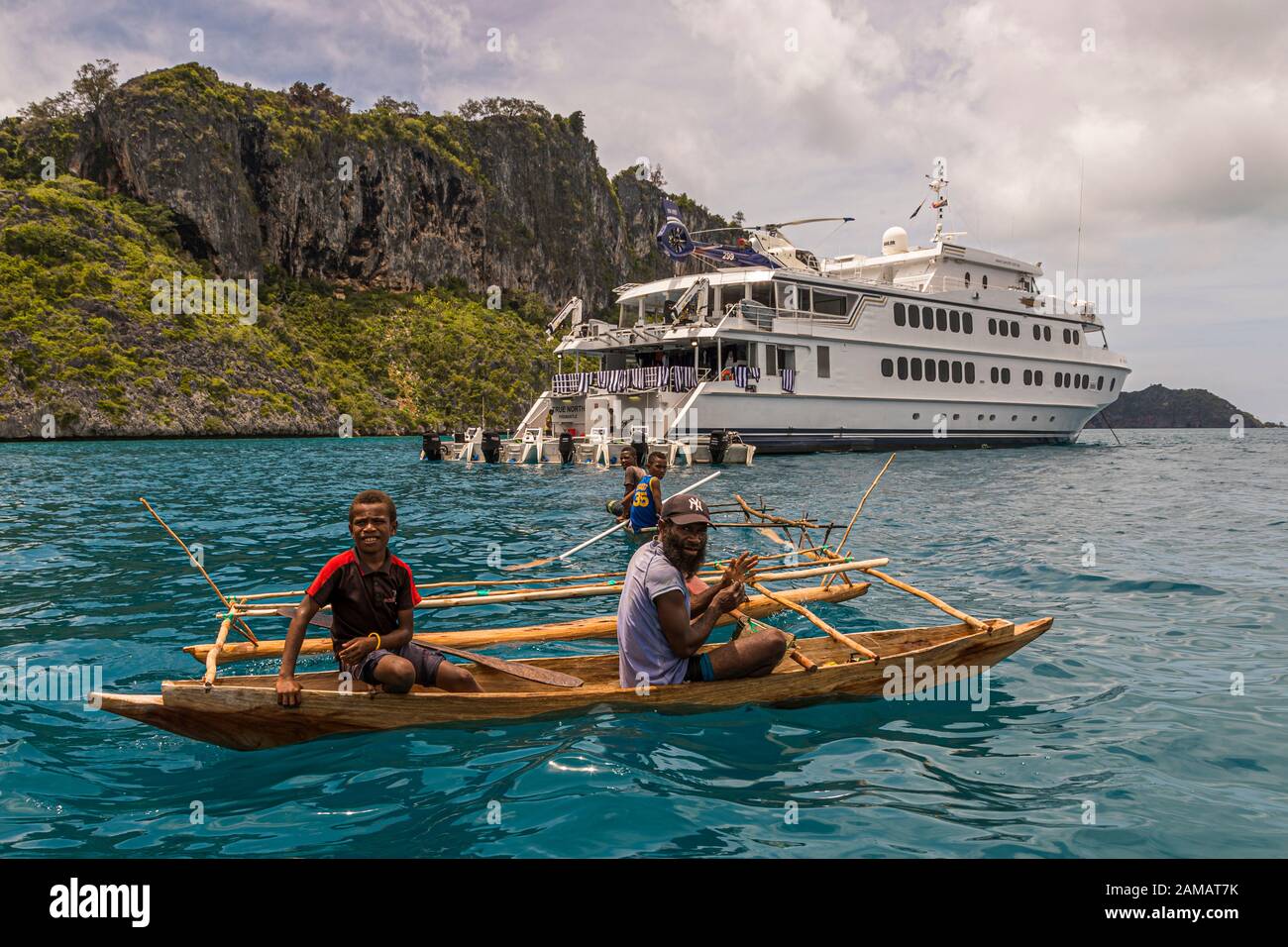 Outrigger Canoe di fronte al vero Nord a Panasia Island, Papua Nuova Guinea. Le canoe Outrigger non sono limitate nella loro manovrabilità nelle acque sopra i coralli. Il vero Nord, d'altra parte, deve navigare molto attentamente nonostante la bassa tirata Foto Stock