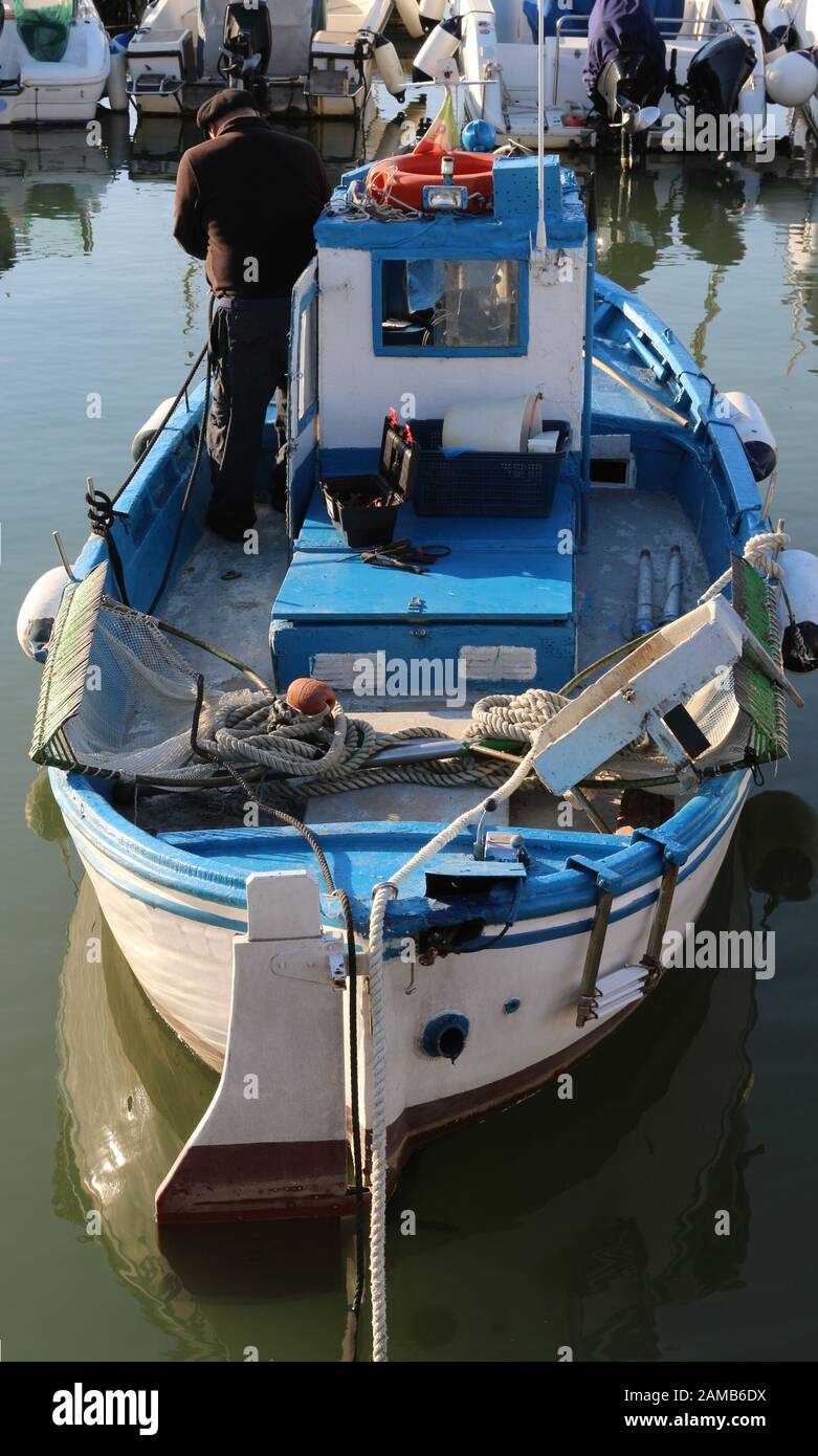 Un pescatore che lavora su una nave da pesca nel porto di Fiumicino, Roma, Italia Foto Stock