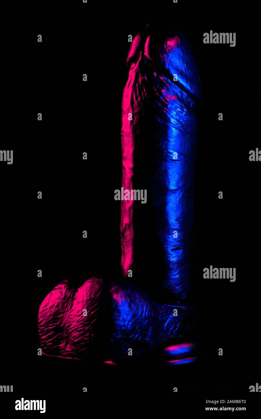 Dildo nero in luce al neon blu e viola. Giocattolo adulto dal negozio di sesso per stimolazione vaginale o anale Foto Stock