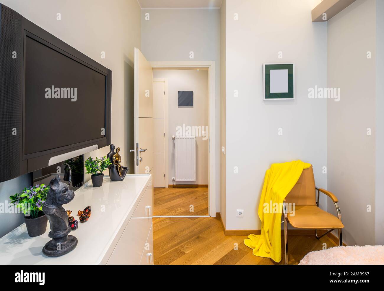 Porta aperta verso la sala dalla sala. TV a parete. Plaid giallo sulla sedia. Foto Stock