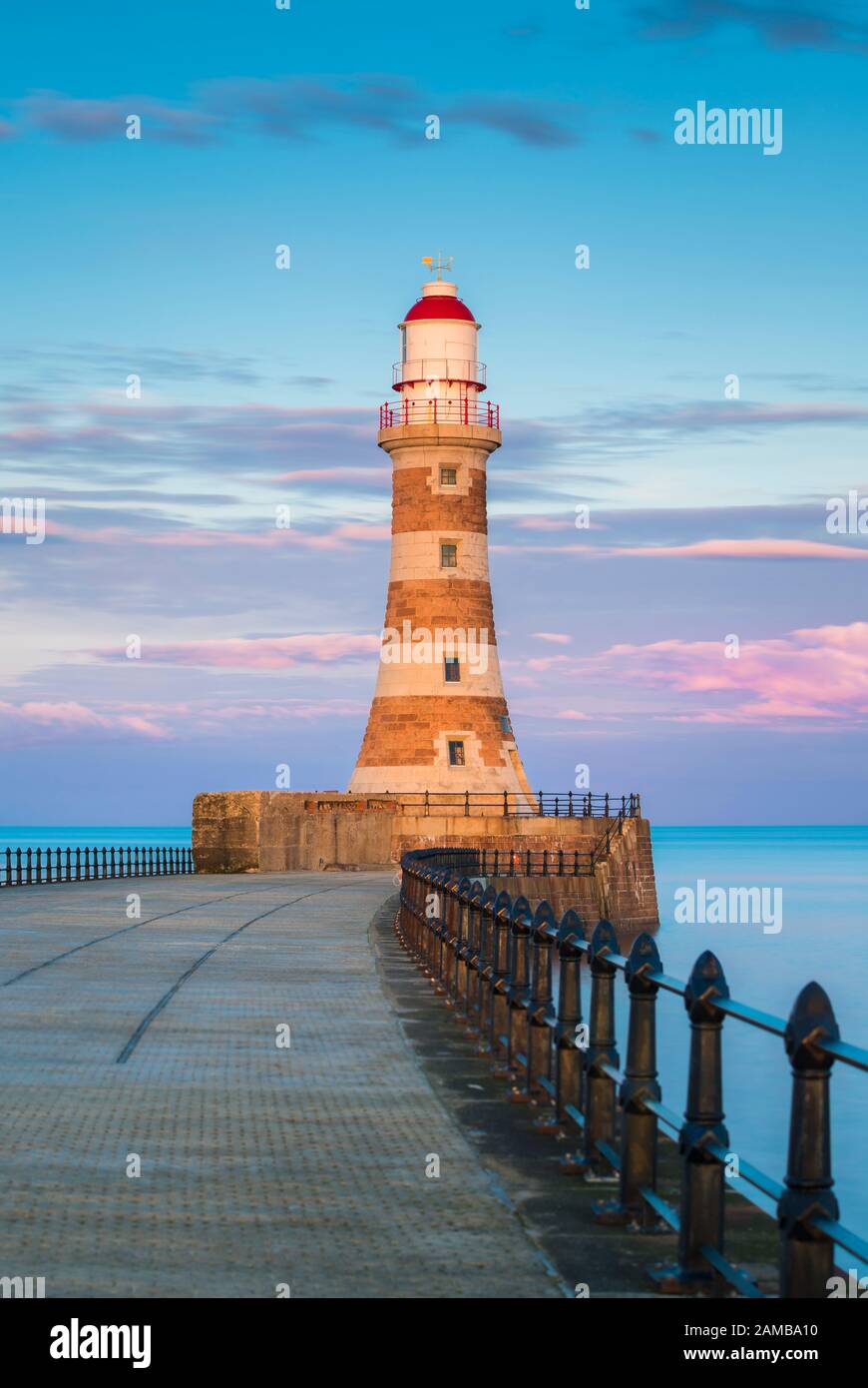 Una meravigliosa tavolozza di colori pastello al tramonto al Roker Pier, Sunderland, le ringhiere che conducono al faro che si erge orgogliosamente nel Mare del Nord. Foto Stock