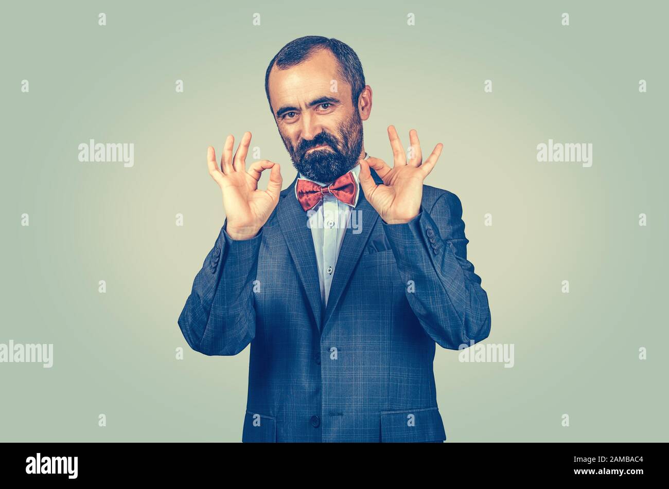 Sicuro uomo d'affari con bearded che mostra il segno giusto con entrambe le mani, le dita isolate sullo sfondo verde della parete. Emozione umana, espressione del volto, simbolo, corpo Foto Stock