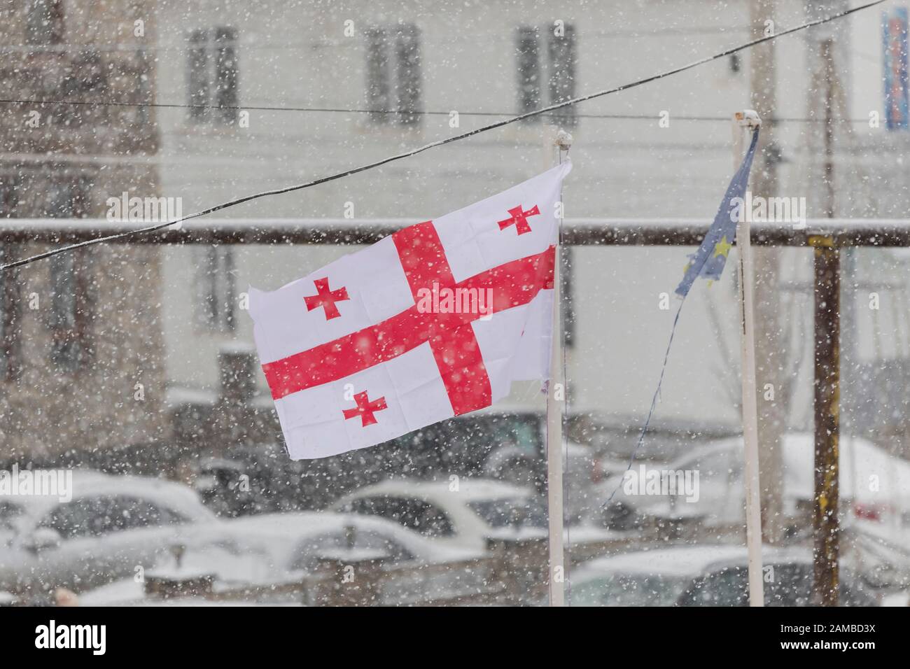Bandiera georgiana ondeggiante nel vento in una nevicata Foto Stock