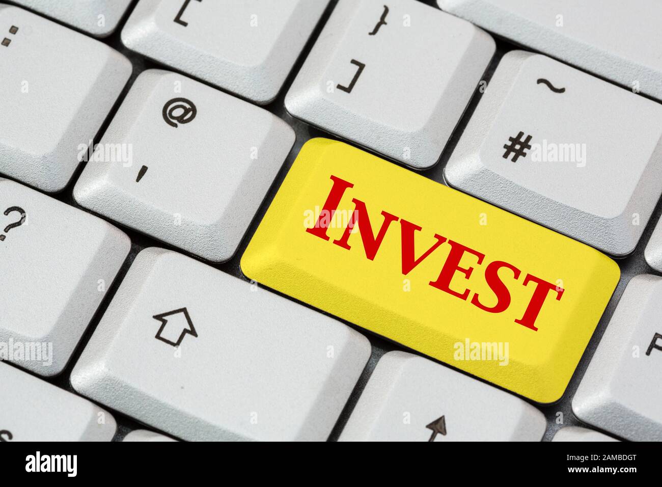 Una tastiera con Invest scritta in rosso su un tasto di invio giallo. Concetto di investimento. Inghilterra, Regno Unito, Gran Bretagna Foto Stock