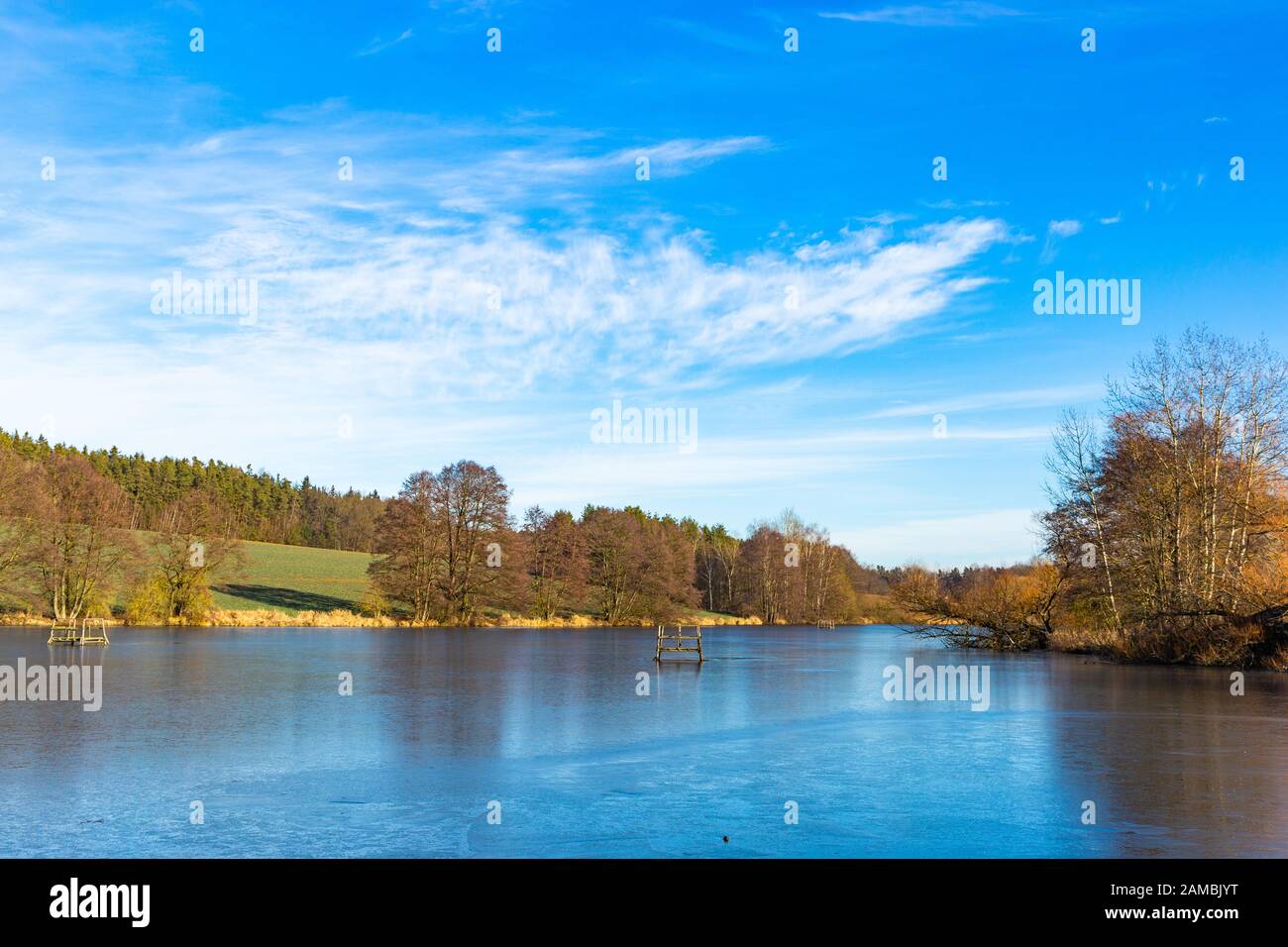 Lago primaverile in campagna ceca. Cielo blu, campo verde e acqua ghiacciata. Foto Stock
