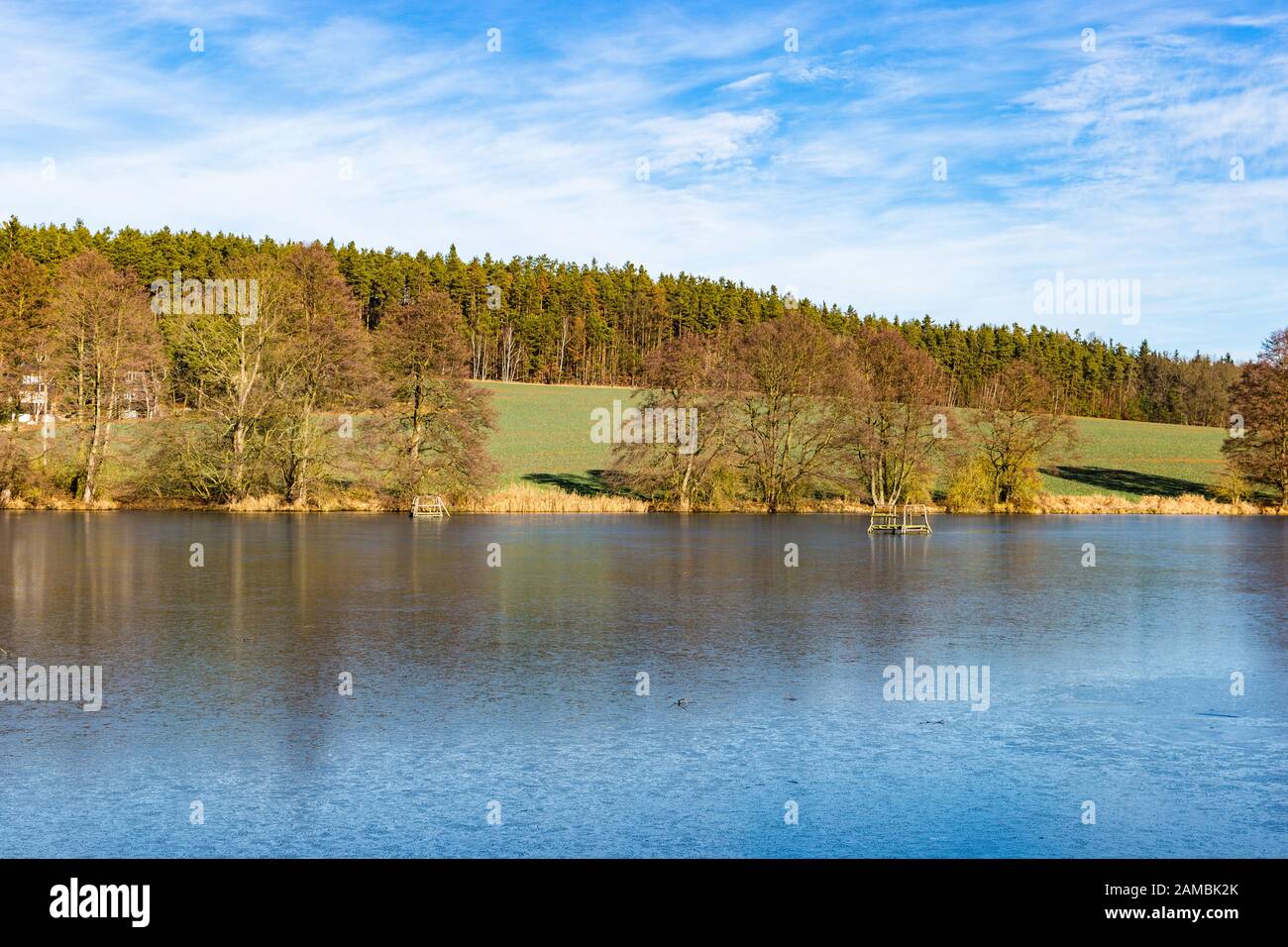 Lago primaverile in campagna ceca. Cielo blu, campo verde e acqua ghiacciata. Foto Stock