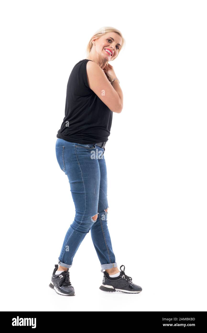 Donna bionda felice di mezza età che tocca e regola i capelli nella coda. Corpo intero isolato su sfondo bianco. Foto Stock