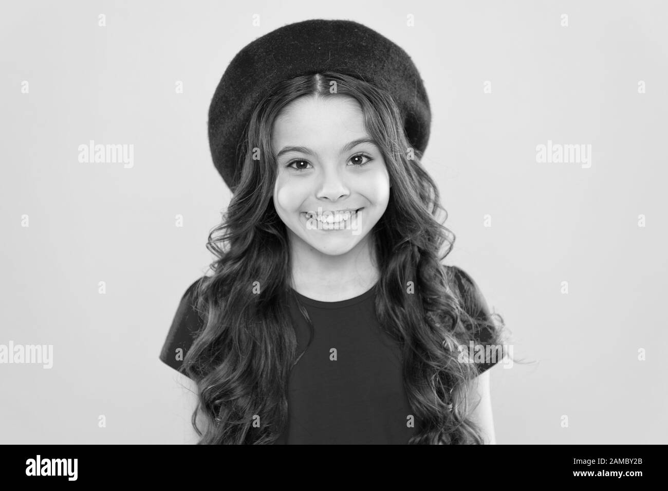 Infanzia. parrucchiere. estate moda e bellezza. parisian bambino su sfondo giallo. Felice ragazza con lunghi capelli ricci in beret. bambina in stile francese hat. Moda ritratto della ragazza. Foto Stock