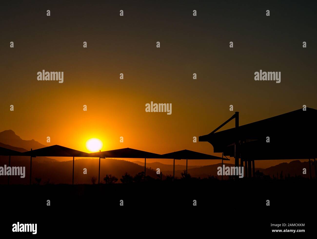 Silhouette di montagne e tendaggi in cantina con suggestivo tramonto arancione, Franschhoek, Sud Africa Foto Stock