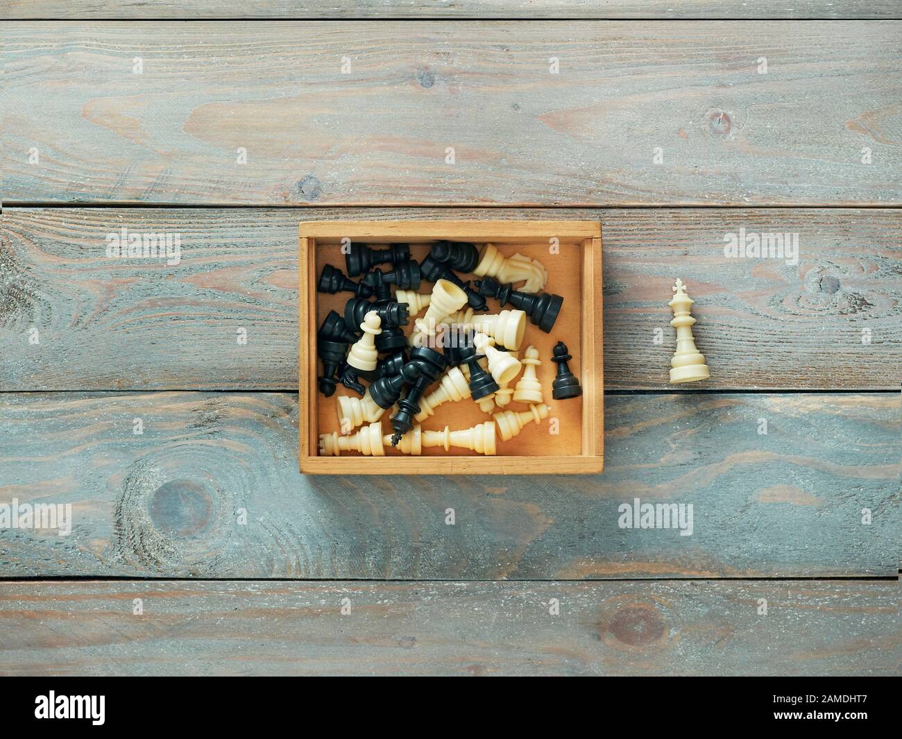 Pezzi di scacchi in una scatola di legno con il re al di fuori della casella Foto Stock