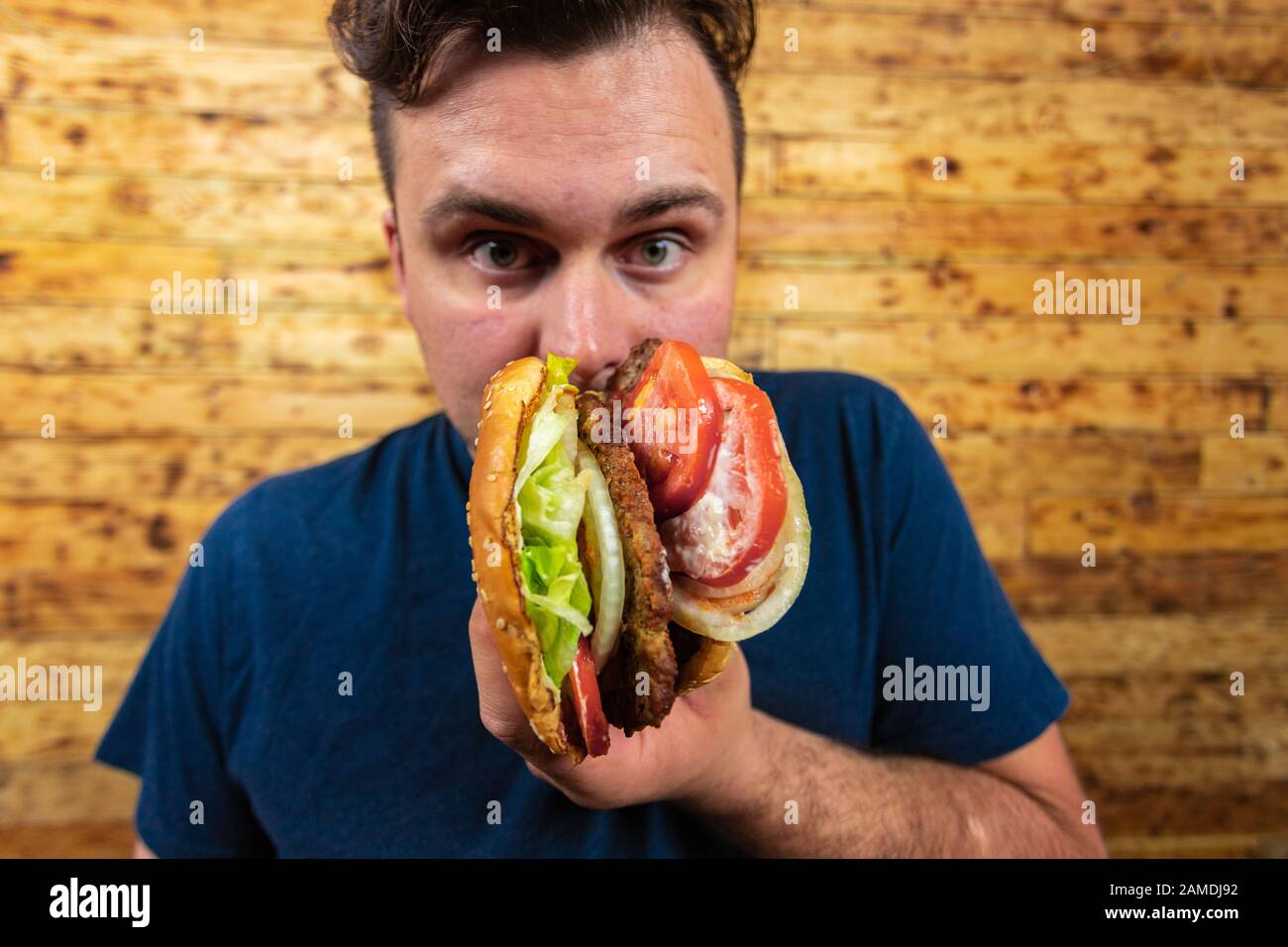 Giovane bell'uomo sta posando con il suo hamburger gustoso e sta per goderlo. Foto Stock