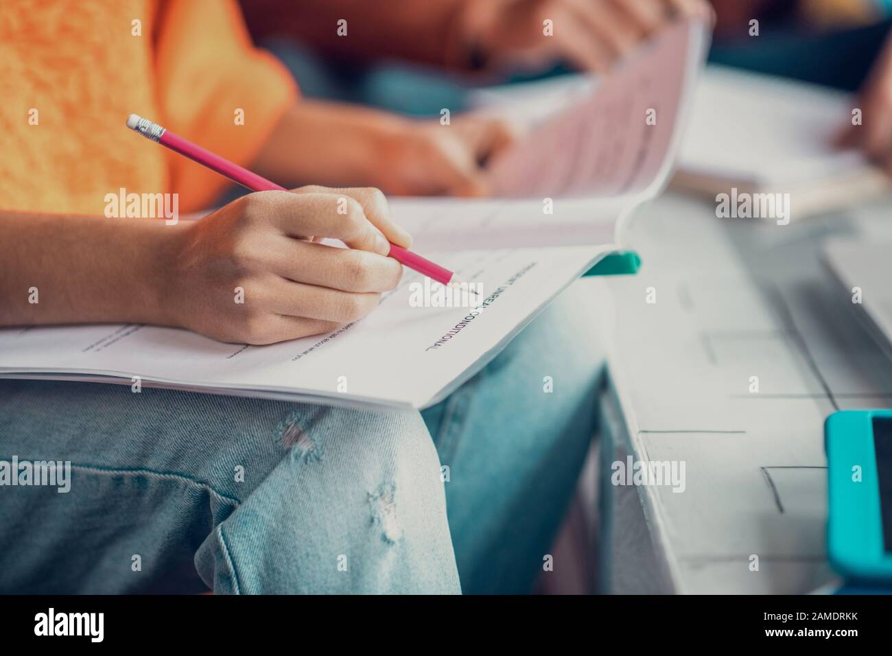 Primo piano dello studente che indossa jeans tenendo matita mentre si fa appunti Foto Stock