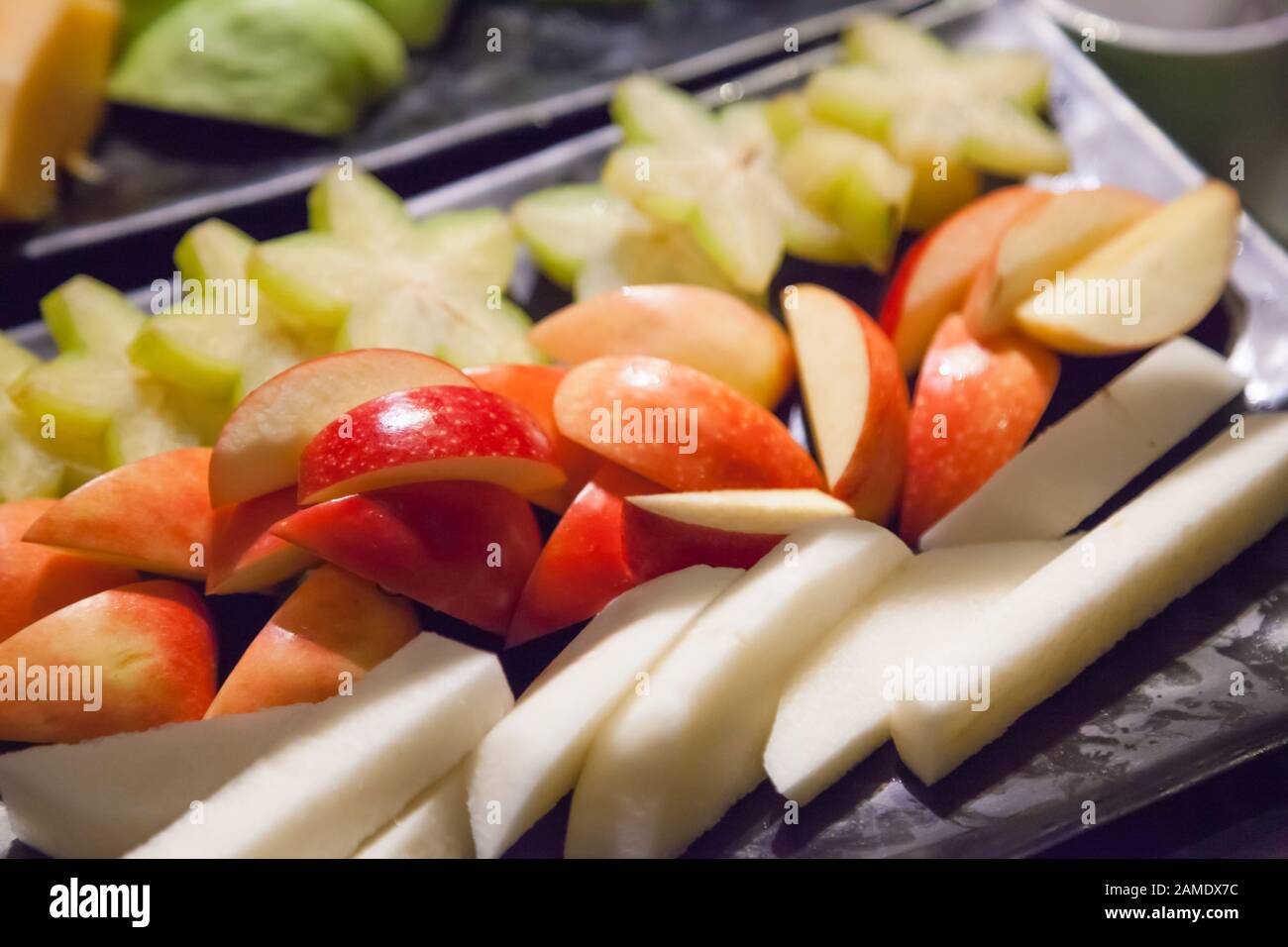 Frutta fresca e assortita di stagione tropicale asiatica (mela, frutta di stellato, yam o jicama) in vassoio nero. Cibo vegetariano e vegano, naturale e Biologico Foto Stock