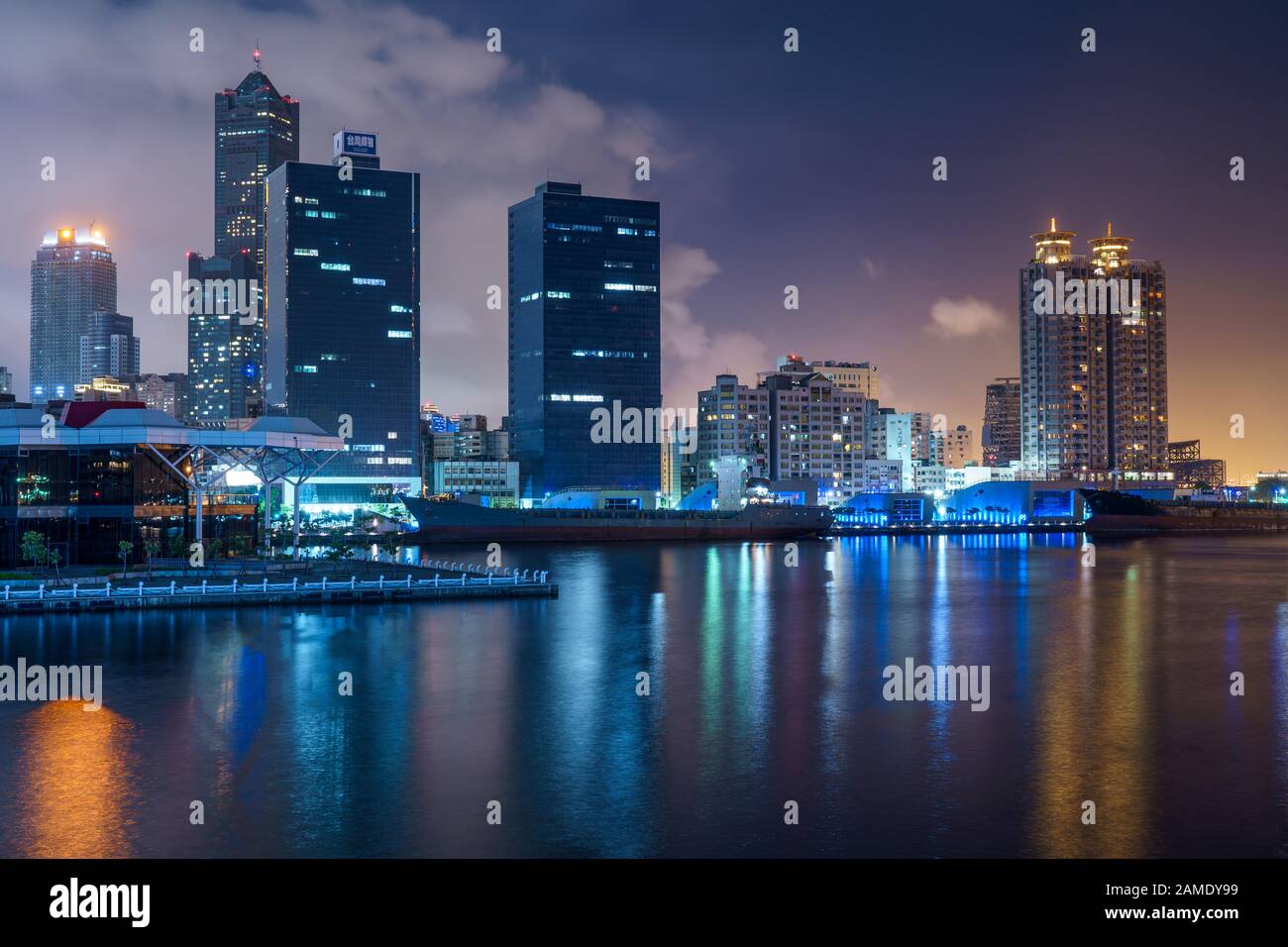 Le luci della città e lo skyline della moderna città taiwanese Kaohsiung si riflettono in acqua di notte Foto Stock