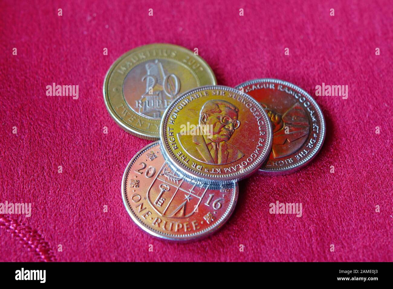 Monete di rupia mauriziana su sfondo rosso. Il codice di valuta per Rupees è MUR, e il simbolo di valuta è ₨. Foto Stock