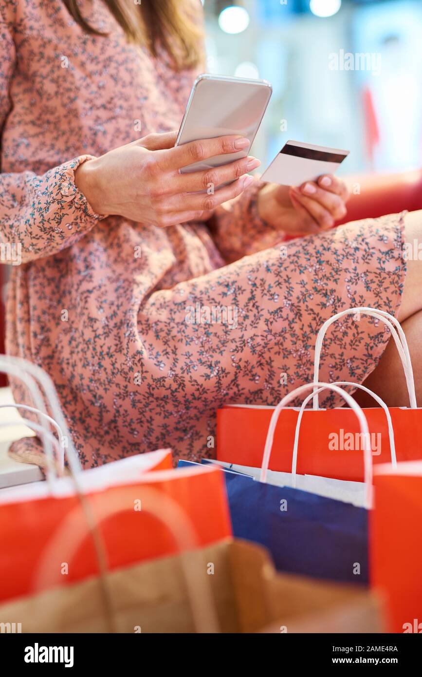 Ragazza che usa il telefono cellulare e la carta di credito durante lo shopping online Foto Stock