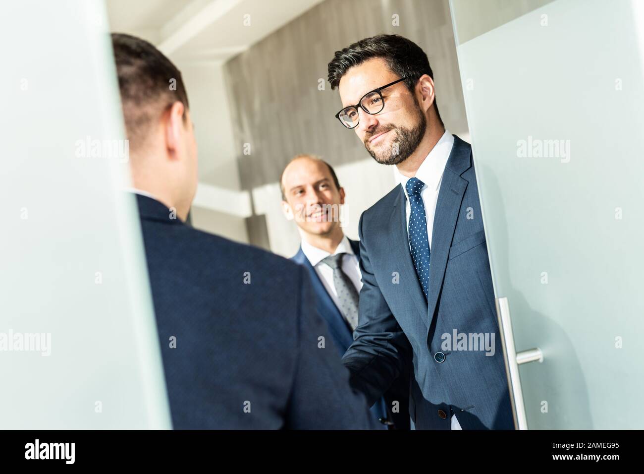 Gruppo di fiduciosi uomini d'affari salutano con una stretta di mano durante la riunione d'affari in ufficio moderno o chiudendo l'accordo di trattativa scuotendo le mani. Foto Stock