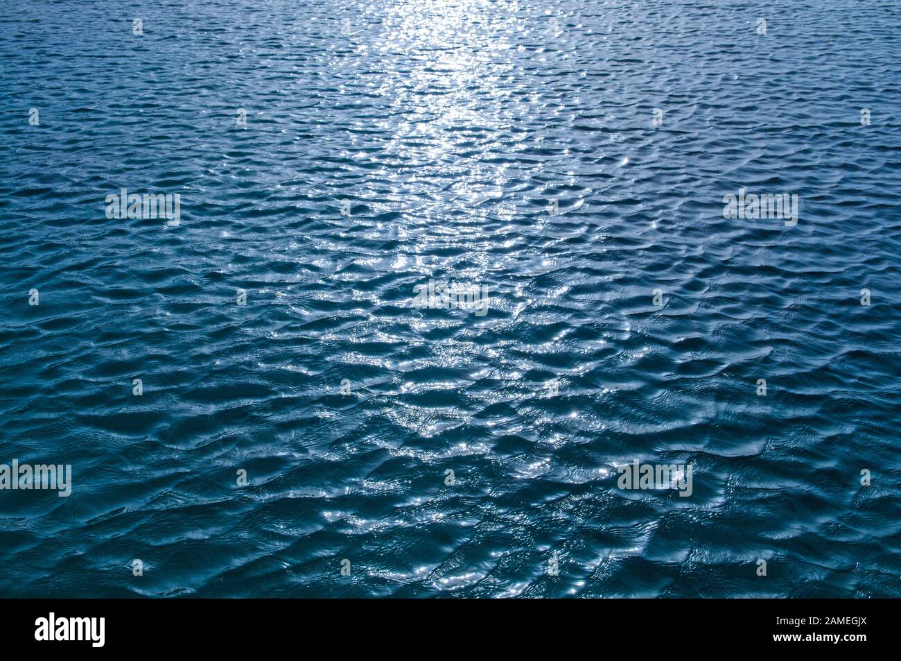 Piccole onde sulla superficie dell'acqua con riflesso del sole Foto Stock