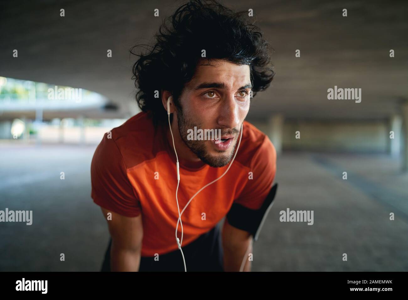 Primo piano di un uomo Stanco corridore con auricolare nelle sue orecchie prendere un riposo dopo correre sulla strada della città - risoluzioni di nuovi anni Foto Stock